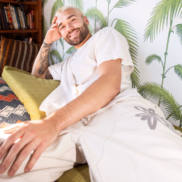 Cory Grimes, a model in Los Angeles, poses for a portrait against palm covered wall paper, giving tropical vibes to a fashion lifestyle shoot in Lost Angeles for photographer, Jonathan Hanson.