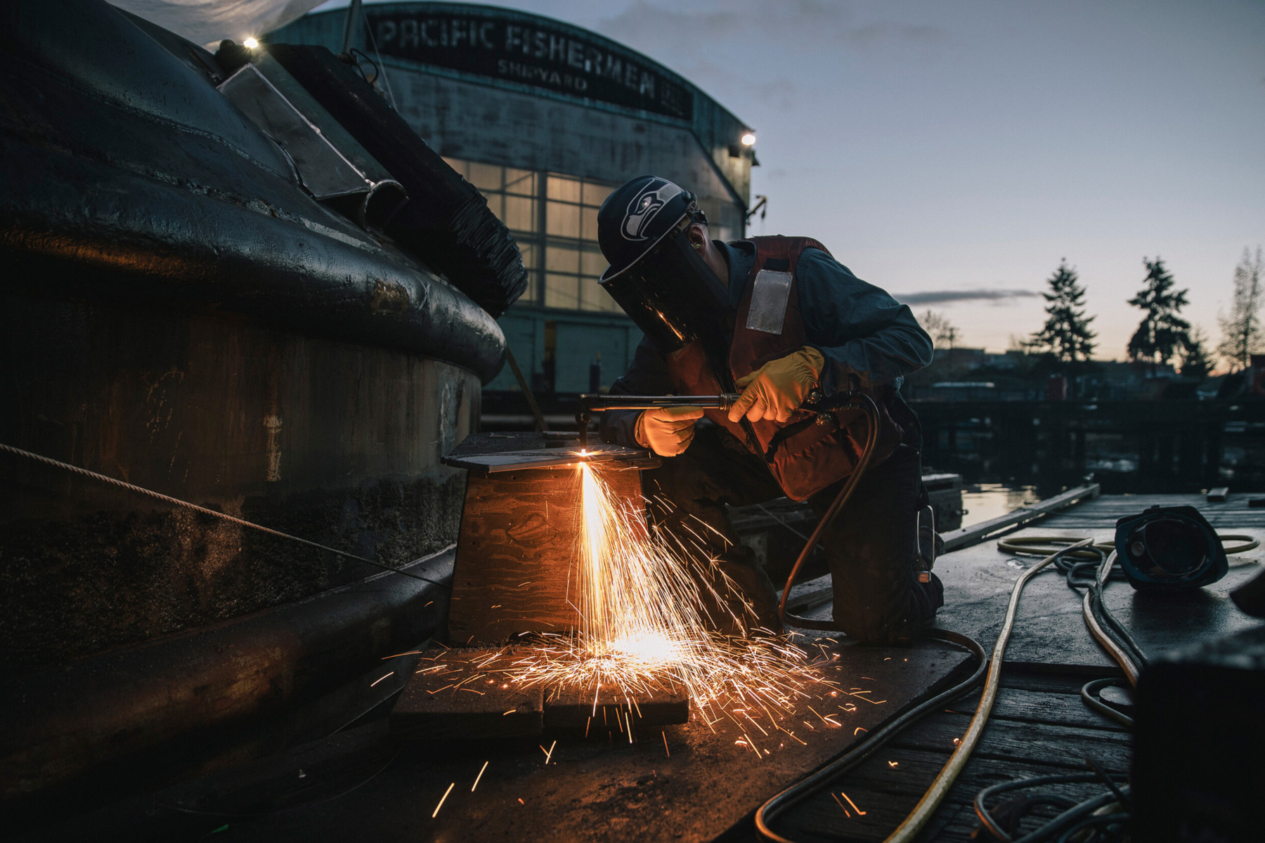 A welder makes a welder during a moody sunset in Alaska, photographed by Travis Gillett.