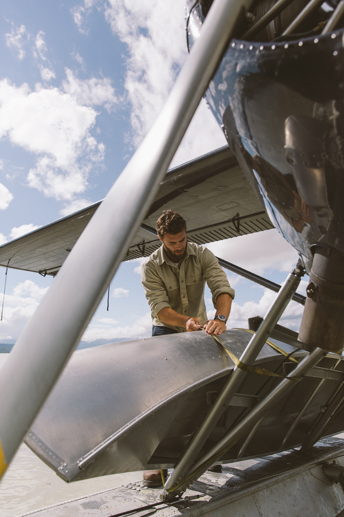 An outdoorsman ties a canoe to his sea plane in Alaska. Photographed by Travis Gillett and Unrivaled.