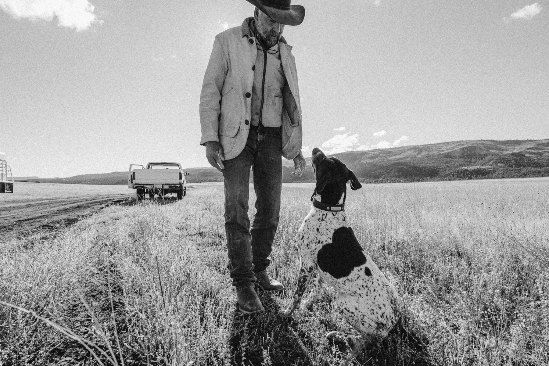 A rancher and his dog in are in an open field in this black and white photo taken in rural Texas.