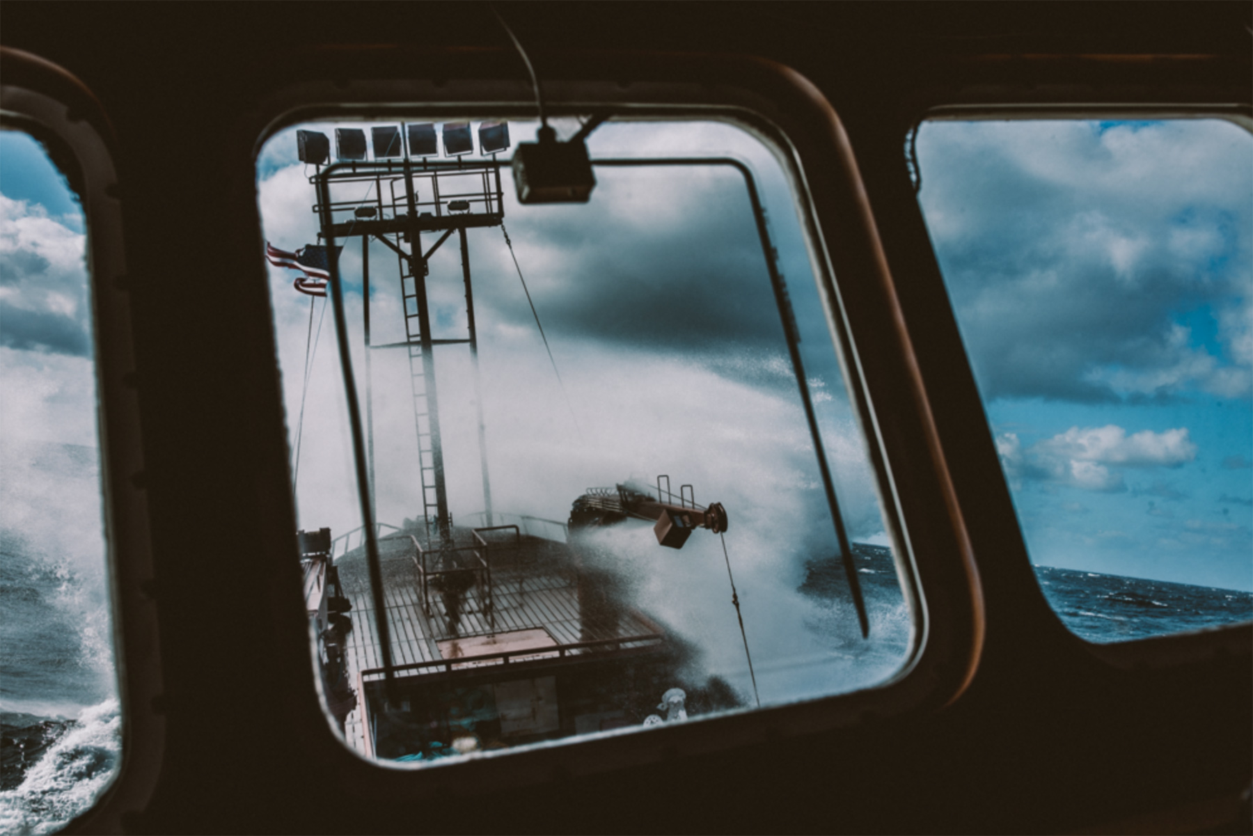 Waves crash over a fishing vessel is this image, taken in Alaska by photographer Travis Gillett. Repped by Unrivaled Productions.