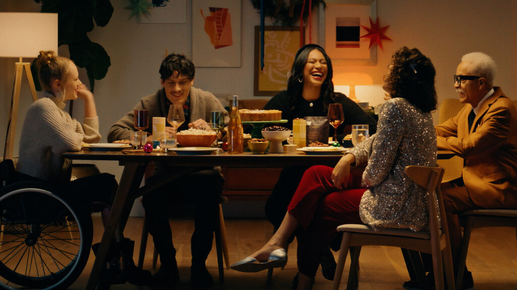 A group of friends and family share a meal around a table during the holidays.