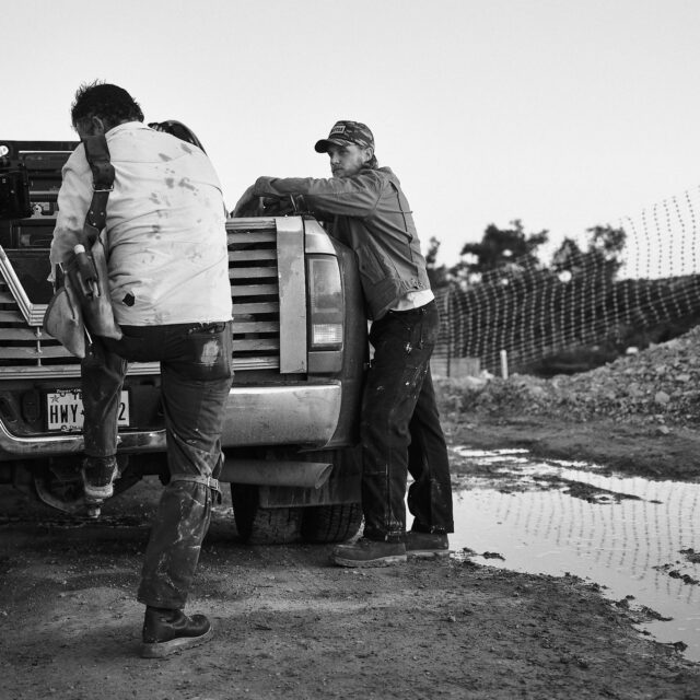 Tw construction works stand at their pick up truck on a worksite in their Tecovas workwear boots.