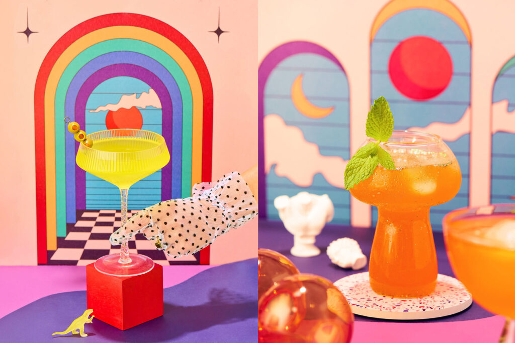 This dazzling image transforms classic cocktails into surreal works of art. On the left, a bright yellow martini—garnished with olives—hovers above a bold, checkerboard portal, drawing us into a dreamlike universe. The delicate gloved hand adds a touch of old-school glamour, while a tiny plastic dinosaur injects playful nostalgia. On the right, a vibrant orange cocktail shimmers in a curvaceous glass, topped with a fresh mint sprig. The hazy reflections, terrazzo coaster, and sculptural decor give the scene a retro-futuristic edge, evoking the golden age of lounge culture with a modern twist.